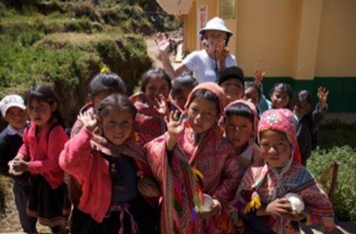 Paula Vail waving with a group of children in Peru